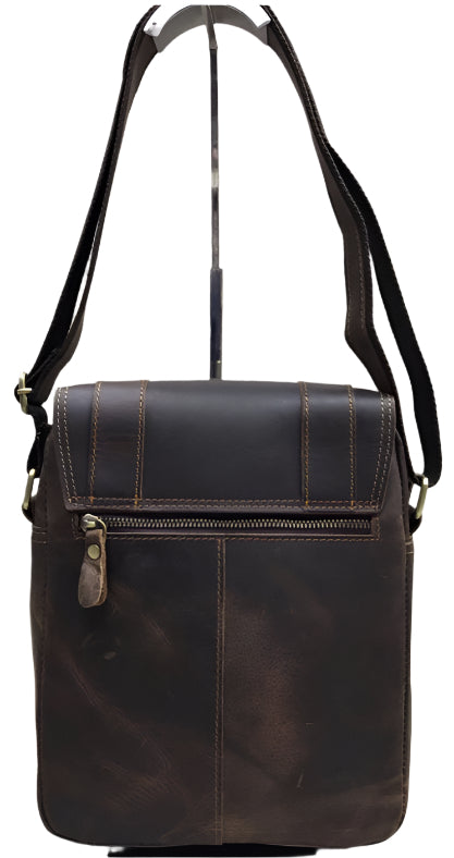 Brown leather satchel bag with visible stitching and hardware on a wooden surface.