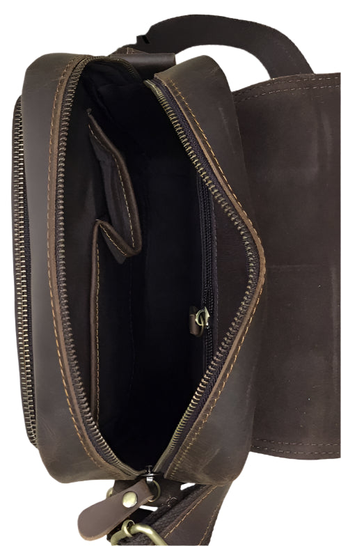 Brown leather satchel bag with visible stitching and hardware on a wooden surface.