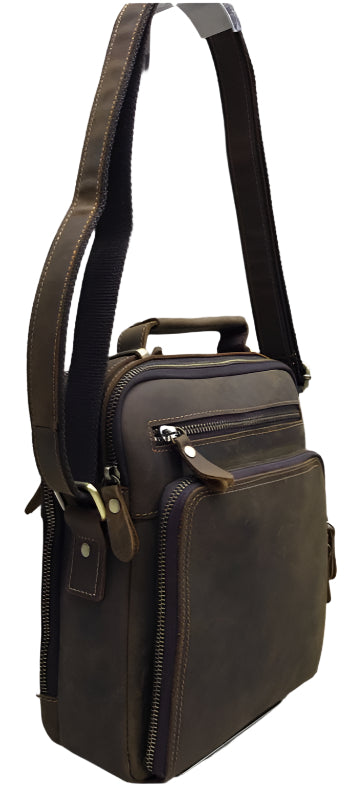Brown leather bag with shoulder strap on a wooden floor background