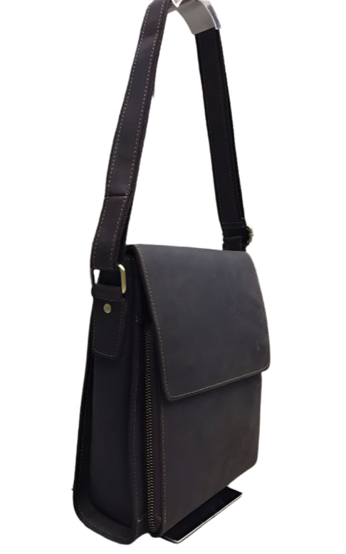 Black leather bag with shoulder strap on a wooden floor background